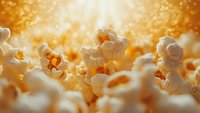 Fresh popcorn with golden bokeh background, extreme close-up view showing texture and detail for food photography and snack advertising.