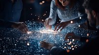 Magical glowing particles float between diverse business team hands in dark meeting room, creating ethereal connection effect for technology concept.