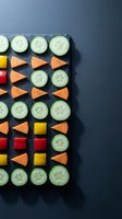 Fresh cucumber slices and colorful carrot pieces arranged in geometric pattern on dark slate board for healthy snacking and meal preparation concepts.
