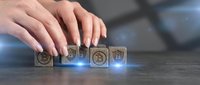 Female hands arranging wooden blocks with bitcoin symbols on dark surface with blue digital glow effects for cryptocurrency and blockchain technology concepts.