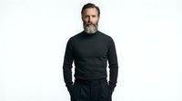 Middle-aged Caucasian man with full beard wearing dark charcoal crew neck sweater, hands in pockets, isolated on white background for apparel and fashion design mockups.