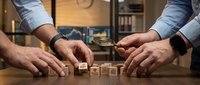 Business team building wooden blocks spelling TEAM on office desk representing teamwork collaboration and corporate strategy development.