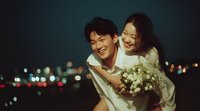 Happy Asian couple embracing at night with city lights bokeh background. Romantic wedding celebration moment with bride holding white flowers outdoors.