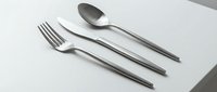 Elegant stainless steel cutlery set with fork, knife, and spoon on a white surface, showcasing modern minimalist design for dining and tableware concepts.