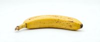 Ripe yellow banana with brown spots isolated on white background, ready for food and nutrition design projects.