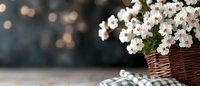White flowers in wicker basket on wooden table with soft bokeh lights background creating cozy home decor atmosphere for spring interior design.