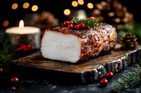 Glazed holiday ham with cranberries and pine garnish on rustic wooden board, festive Christmas dinner centerpiece with warm candlelight and bokeh background.