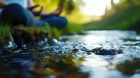 Tranquil stream with crystal clear water flowing over rocks, creating gentle ripples and splashes in natural sunlight, surrounded by lush greenery and moss.