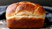 Fresh baked homemade bread loaf with golden brown crust and soft white interior perfect for bakery menus restaurant advertising and food blogs.
