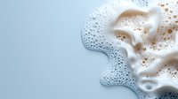 White foam bubbles spreading across light blue surface creating abstract cleaning soap suds pattern for hygiene and freshness concepts.