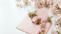 Pink notebook with delicate spring flowers and green herbs arranged on soft pastel background for feminine stationery and botanical design projects.