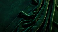 Luxurious emerald green velvet fabric with rich folds and drapes, showcasing soft texture and elegant waves for luxury design, fashion, and interior decor projects.