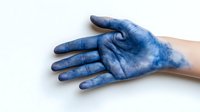 Blue-stained hand showing palm up against white background, demonstrating artistic body painting or dye effect on skin.