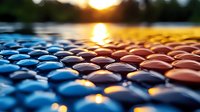 Colorful mosaic pattern of round stones at sunset with golden sun reflection on water surface creating dreamy bokeh effect. Perfect for wellness and spa designs.