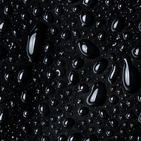 Water drops on dark surface create dramatic contrast with reflective highlights and varying sizes, suitable for abstract backgrounds and nature photography.