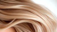 Smooth flowing blonde hair strands in gentle waves creating elegant curves and lines against soft beige background, showcasing natural hair texture and movement.