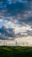 Wind turbines on rolling green hills under dramatic cloudy sky at sunset, renewable energy landscape for sustainable power generation and environmental concepts.