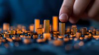 Hand reaching toward miniature city skyline with golden-orange illuminated buildings against dark blue background. Urban planning concept.