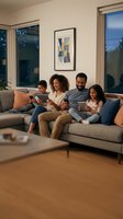 Happy African American family relaxing on sofa using digital tablets together in modern living room during evening at home.