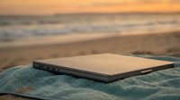 Smartphone with blank screen resting on towel at beach during golden hour sunset, ideal for mobile app marketing and travel technology concepts.
