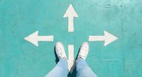 Person standing at crossroads with white directional arrows on turquoise ground showing multiple path choices for decision making and life direction concepts.