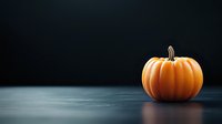 Fresh orange pumpkin on dark background with dramatic lighting and copy space for seasonal autumn and halloween designs.