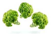 Fresh green broccoli florets floating in air on white background, isolated organic vegetables for healthy eating and cooking concepts.