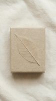 Minimalist eco-friendly gift box with embossed leaf detail on natural kraft paper, sustainable packaging concept for organic products and green business branding.