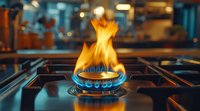 Gas stove burner with bright blue and orange flames in professional kitchen, dramatic close-up shot showing heat and energy consumption in cooking environment.