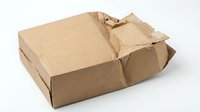 Damaged brown cardboard shipping box with torn packaging isolated on white background for delivery and logistics concepts.