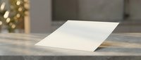 Blank white paper sheet on wooden table with blurred background lights creating warm atmosphere for mockup presentations and design projects.