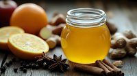 Glass jar of golden honey with fresh oranges, ginger root, star anise and cinnamon sticks on rustic wooden background, natural cold and flu remedies.