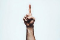 Male hand showing index finger pointing upward against light background, expressing direction, choice, attention or number one gesture. Dramatic lighting creates depth.