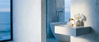 Coastal bathroom interior with modern white sink, minimalist design, and ocean view through large window, featuring contemporary fixtures and natural lighting.