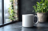 White ceramic coffee mug mockup on dark concrete table near window with green plant. Natural daylight creates soft shadows, minimal composition for branding.