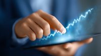 Businessman holding digital tablet with glowing blue financial chart graph showing growth trend, close up view of hands touching screen interface.