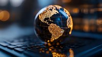 Illuminated globe showing Americas on laptop keyboard with glowing golden lights and bokeh effect in dark blue atmosphere, global business concept.