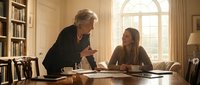 Senior businessman mentor coaching young female professional in elegant office library setting with warm natural lighting and classic interior.