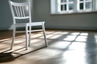 White wooden chair casting dramatic shadows on wooden floor in minimalist interior with natural window light and soft morning atmosphere.