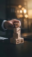 Businessman hand protecting wooden blocks with business icons including shield, growth arrow, dollar sign, gear and lock symbols representing security and success.