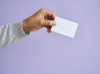 Male hand holding blank white business card against purple background for branding and corporate identity design projects.