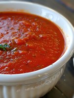 Fresh homemade marinara sauce with herbs and spices in white ceramic bowl, close up view showing rich red color and smooth texture. Great for Italian cuisine.