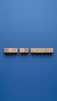 Wooden letter blocks spelling buy or lease on blue background, representing real estate decision, property rental or purchase options for business and finance concepts.