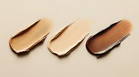 Makeup foundation smears in different skin tone shades from light to dark on beige background, showing cosmetic texture and color range for beauty products.