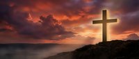 Wooden cross silhouetted against dramatic sunset sky over ocean horizon with rocky coastline for spiritual and religious themes.