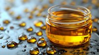 Glass jar with golden honey and scattered amber-colored liquid drops on dark reflective surface creating artistic food composition with natural lighting.