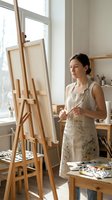 Young Caucasian female artist painting on canvas in bright art studio workspace with easel and art supplies for creative projects and artistic expression.