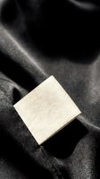Blank white fabric label on dark textile material for clothing branding and garment manufacturing applications.