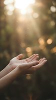 Outstretched open hands reaching toward warm sunlight rays in a bokeh forest, symbolizing prayer, hope, and spiritual connection.