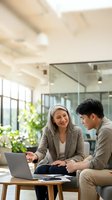 Professional business meeting between mature woman mentor and young man colleague discussing project with laptop in modern office space for corporate teamwork.